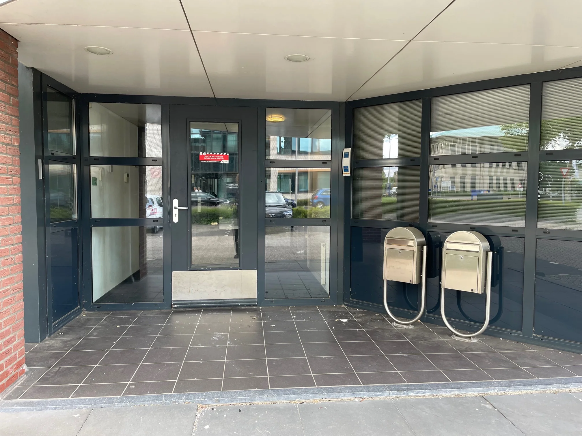 Ingang van een kantoorgebouw aan de Rivium 4e Straat met glazen deuren, twee brievenbussen en een intercom.